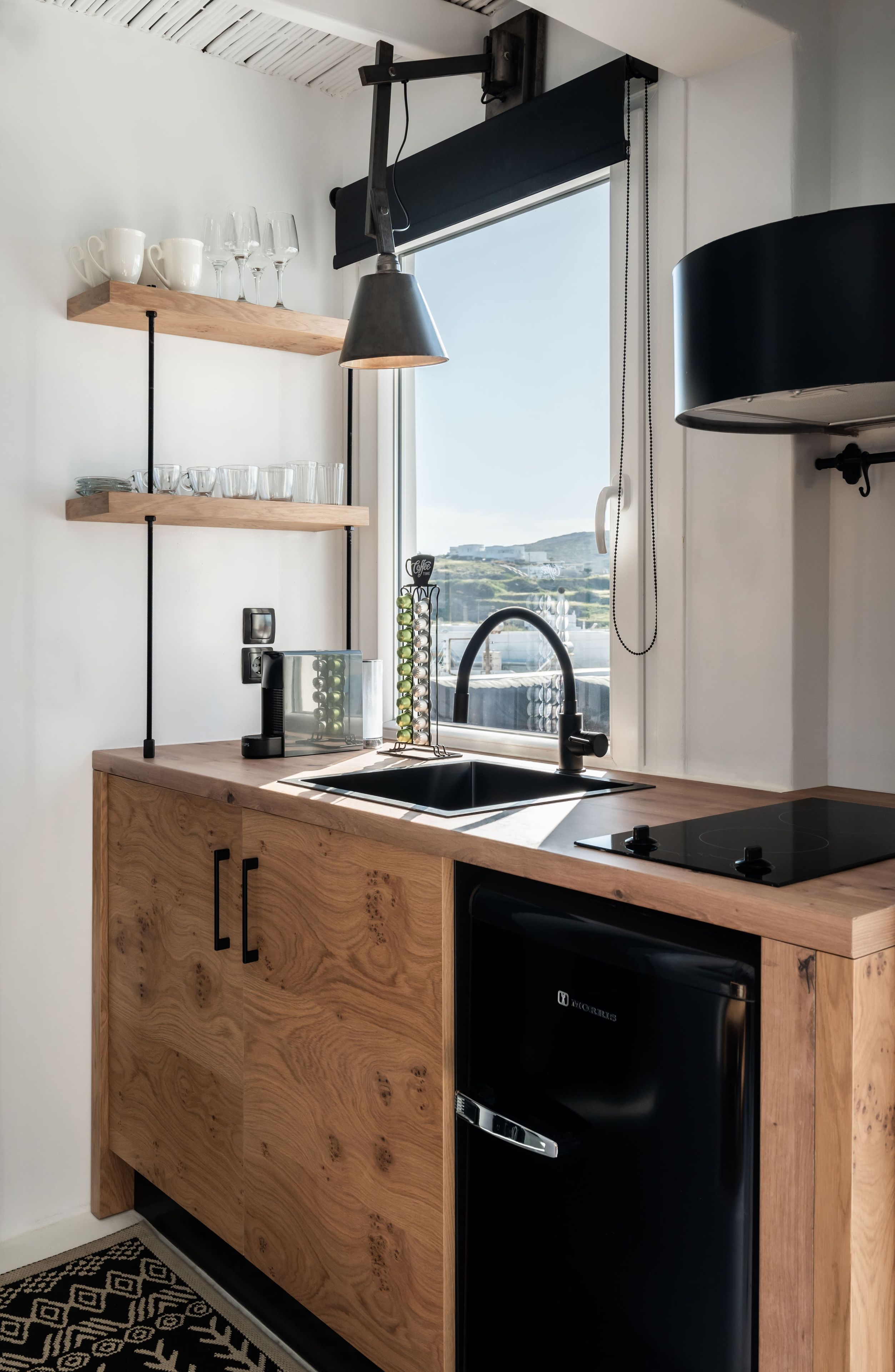 Una cocina moderna con muebles de madera, lavavajillas negro y ventana con vistas panorámicas.