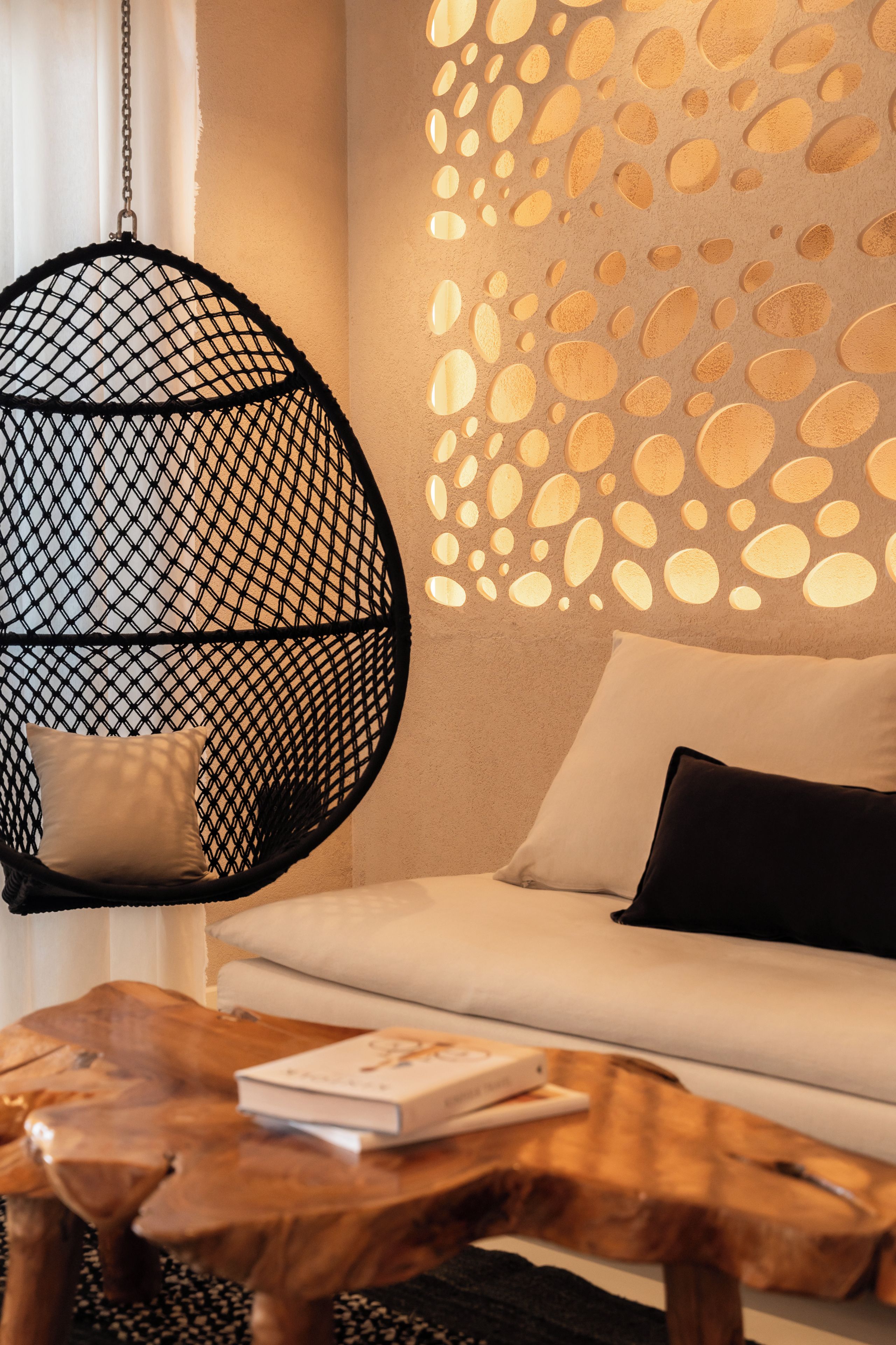 Una sala moderna con un sillón colgante, un sofá y una mesita de centro.