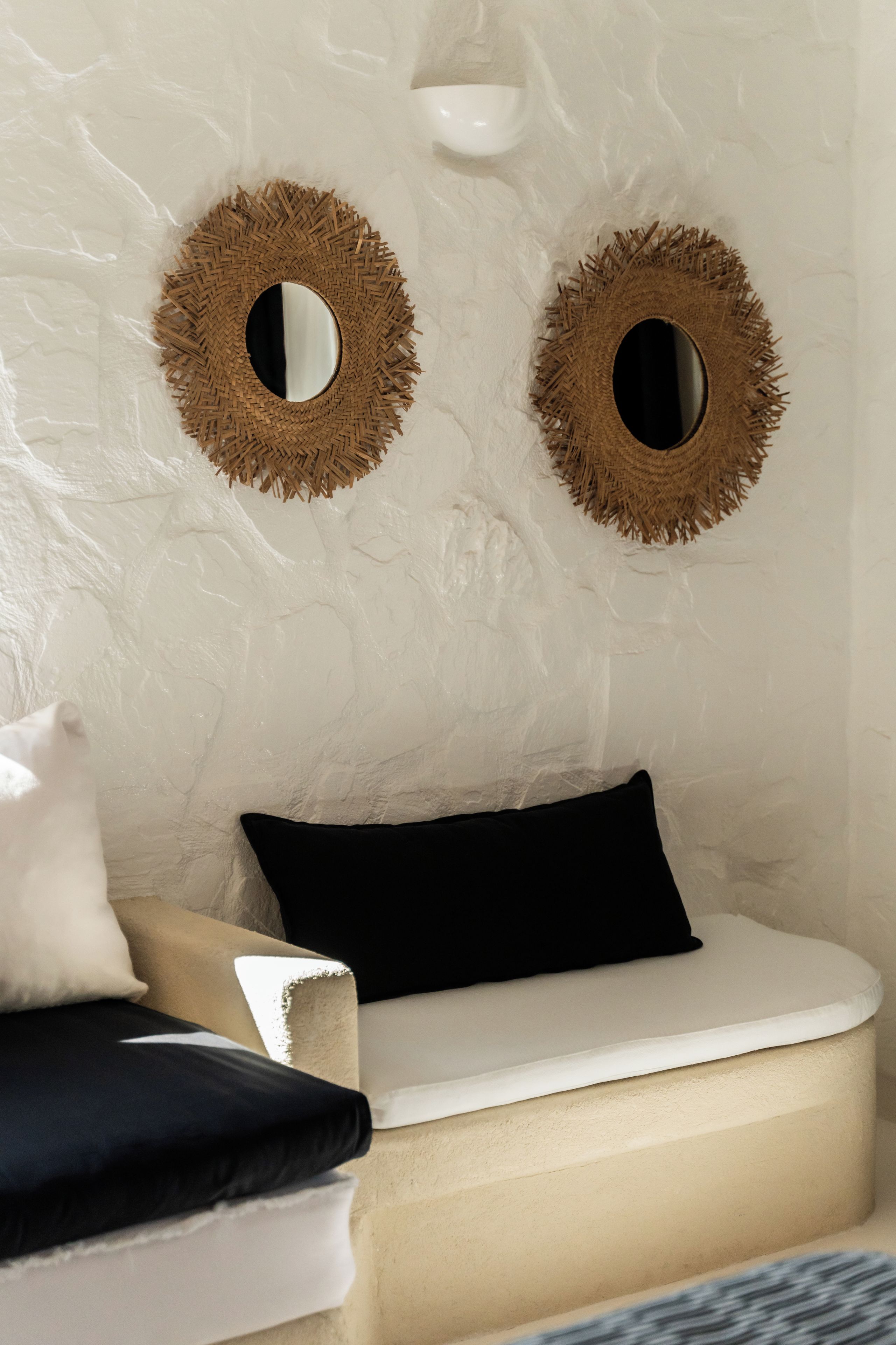 A room with a textured wall, a white sofa with a black cushion, and two circular wall decorations.