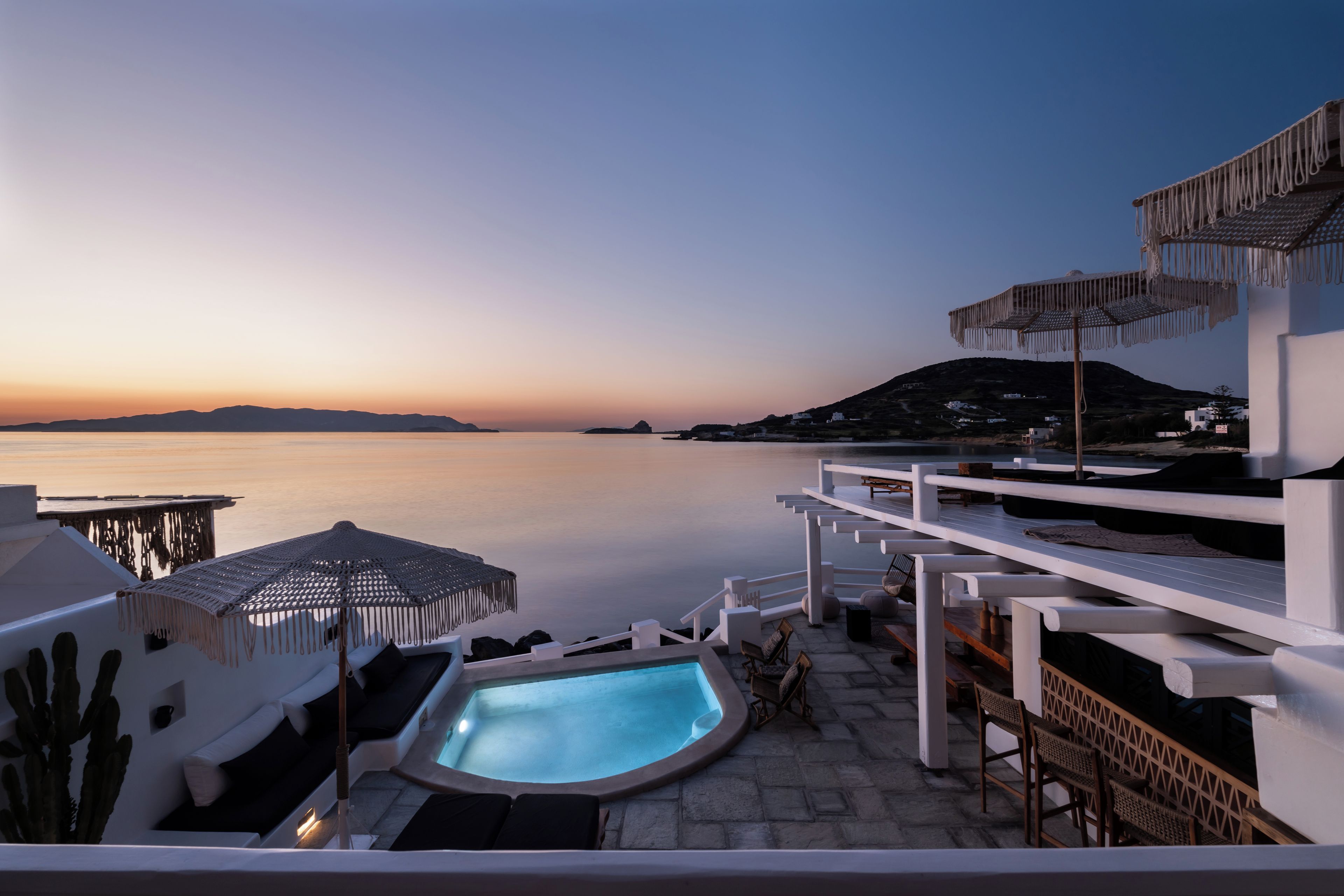 Zona de piscina con vista al mar y al atardecer.
