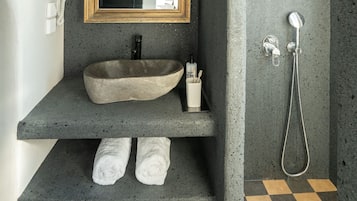 Un baño con lavamanos de piedra, espejo con marco de madera, ducha y piso a cuadros.