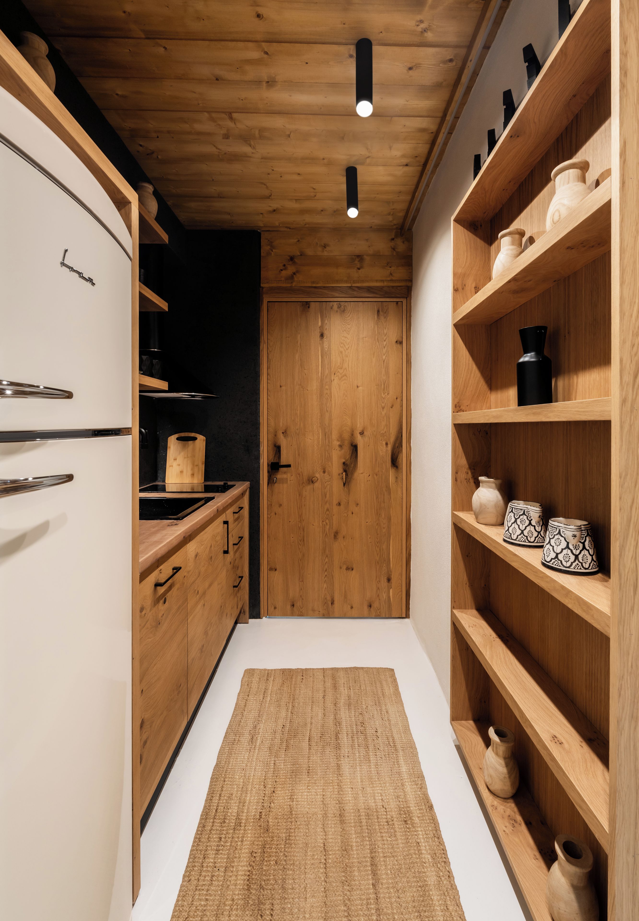 A modern kitchen with wooden cabinetry, a built-in oven, and a black countertop.