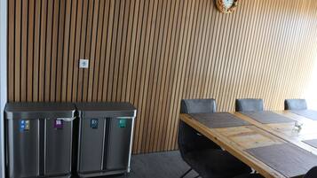 Un salón de conferencias con pared de paneles de madera, un reloj y dos contenedores de basura.