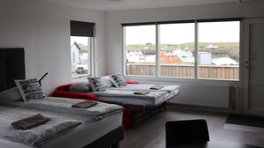 Een moderne hotelkamer met twee bedden, grote ramen en uitzicht op boten en water.