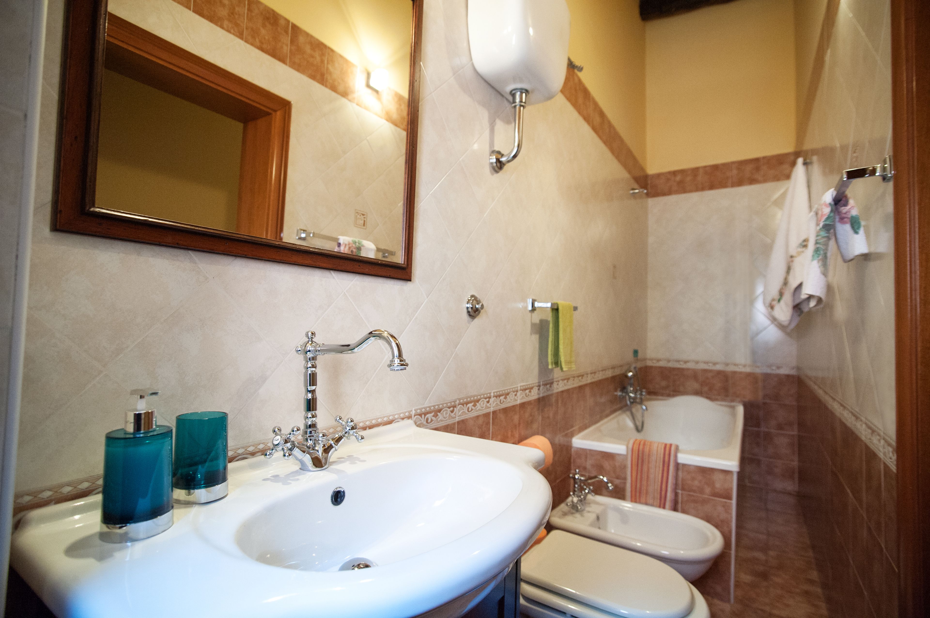 A bathroom with a sink, mirror, towel rack, and a bathtub.