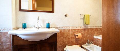 Un baño con lavamanos, inodoro y bidé.