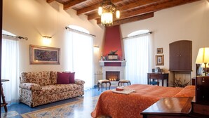 A hotel room with a bed, a sofa, a fireplace, and a chandelier. - VinsLounge B&B (Barletta)