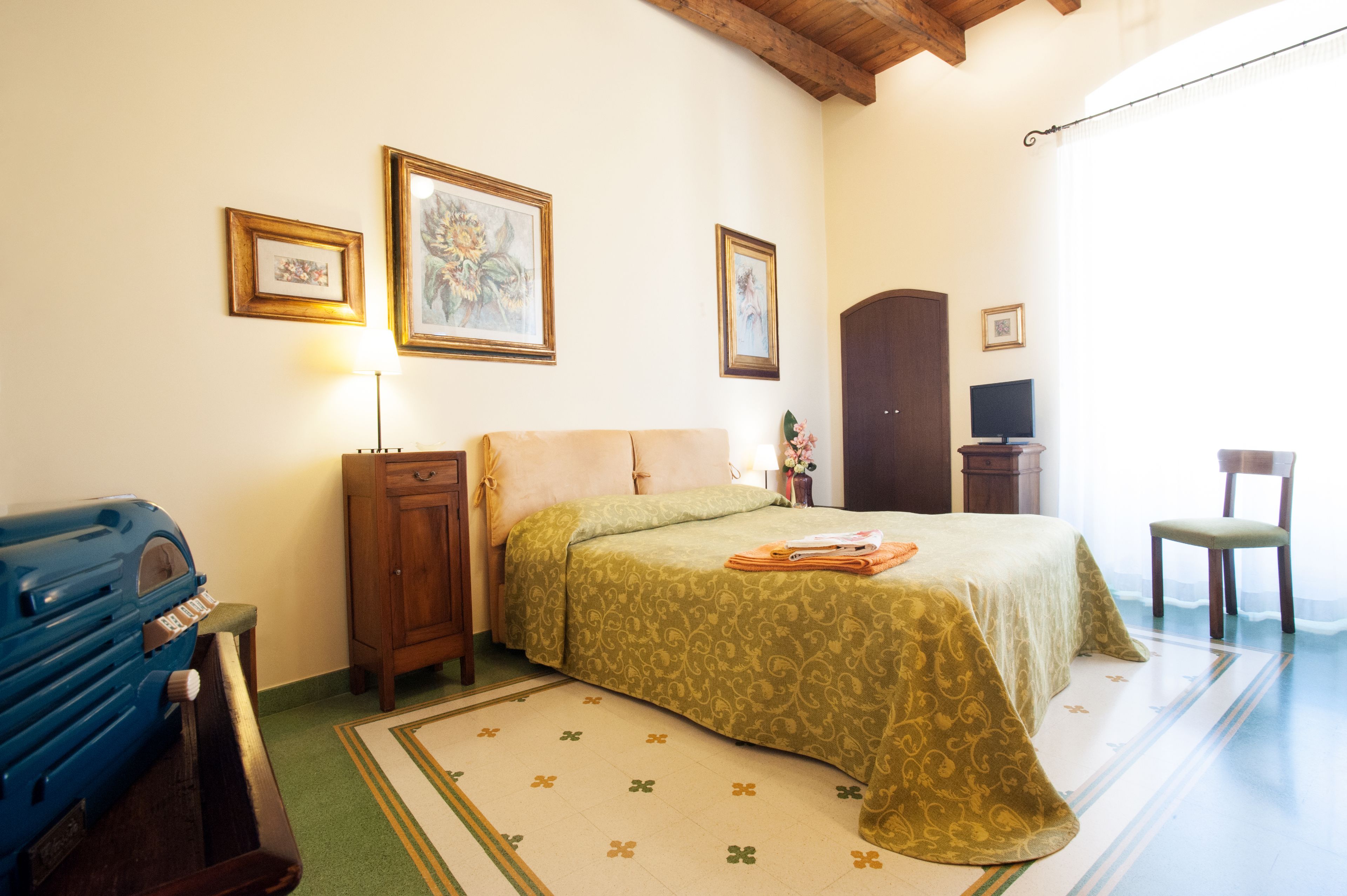 Un dormitorio con cama, cómoda, silla, televisión y radio.