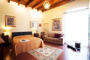 Quarto com cama, sofá, radiador e janela com cortinas.
