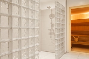 Een moderne badkamer met een douchecabine van glas en een houten sauna.