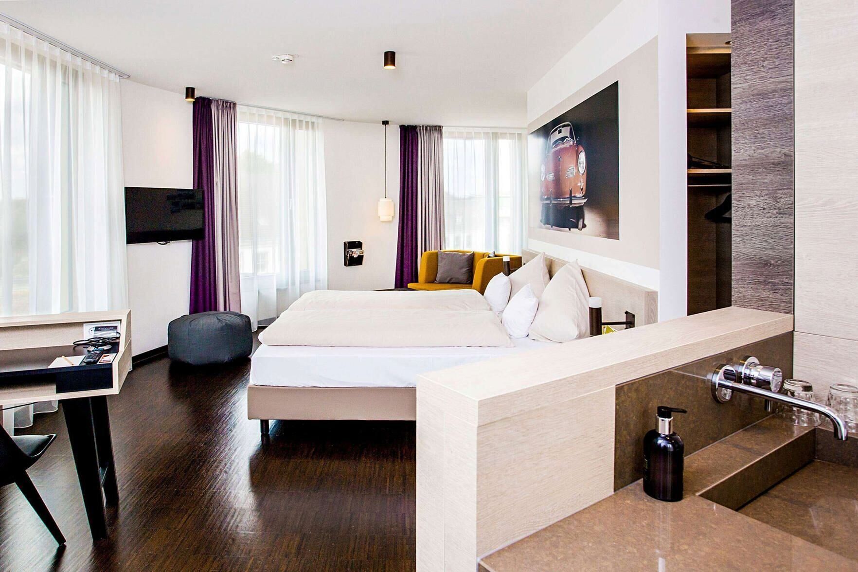 Une chambre d’hôtel moderne équipée d’un lit, d’une table de chevet et d’une cabine de douche intégrée.