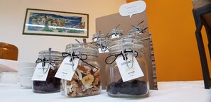 Glass jars with labels on a table, a framed painting on the wall, and a wooden chair. - Hotel Terme di Castel San Pietro (Castel San Pietro Terme)