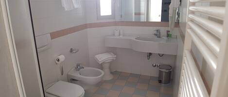 A bathroom with a toilet, bidet, sink, and mirror.