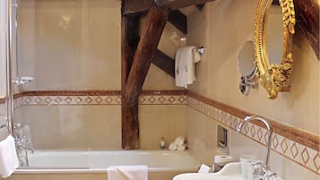 A bathroom with a checkered floor, a bathtub, two toilets, a sink, and a mirror with an ornate frame.
