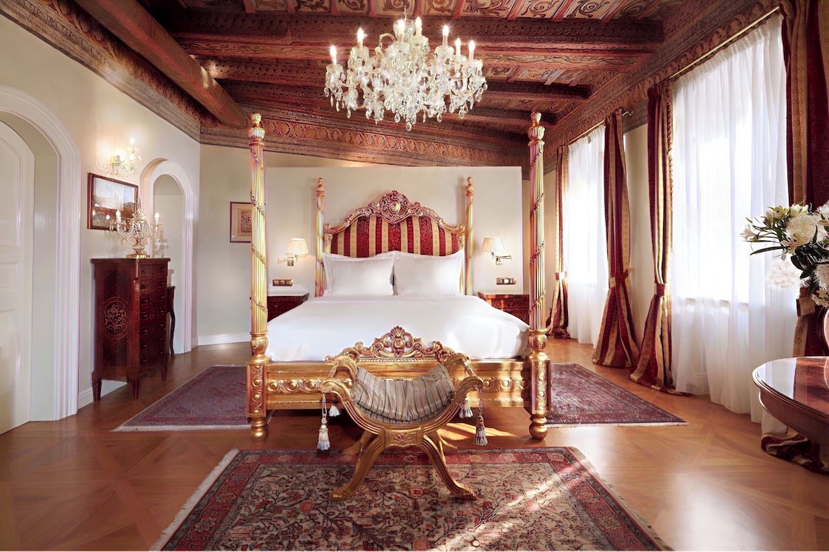 A luxurious bedroom with a four-poster bed, ornate chandelier, and classic decor.