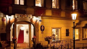 A hotel entrance with a red carpet, a staircase, and a sign above the door. - Alchymist Prague Castle Suites Hotel (Prague)