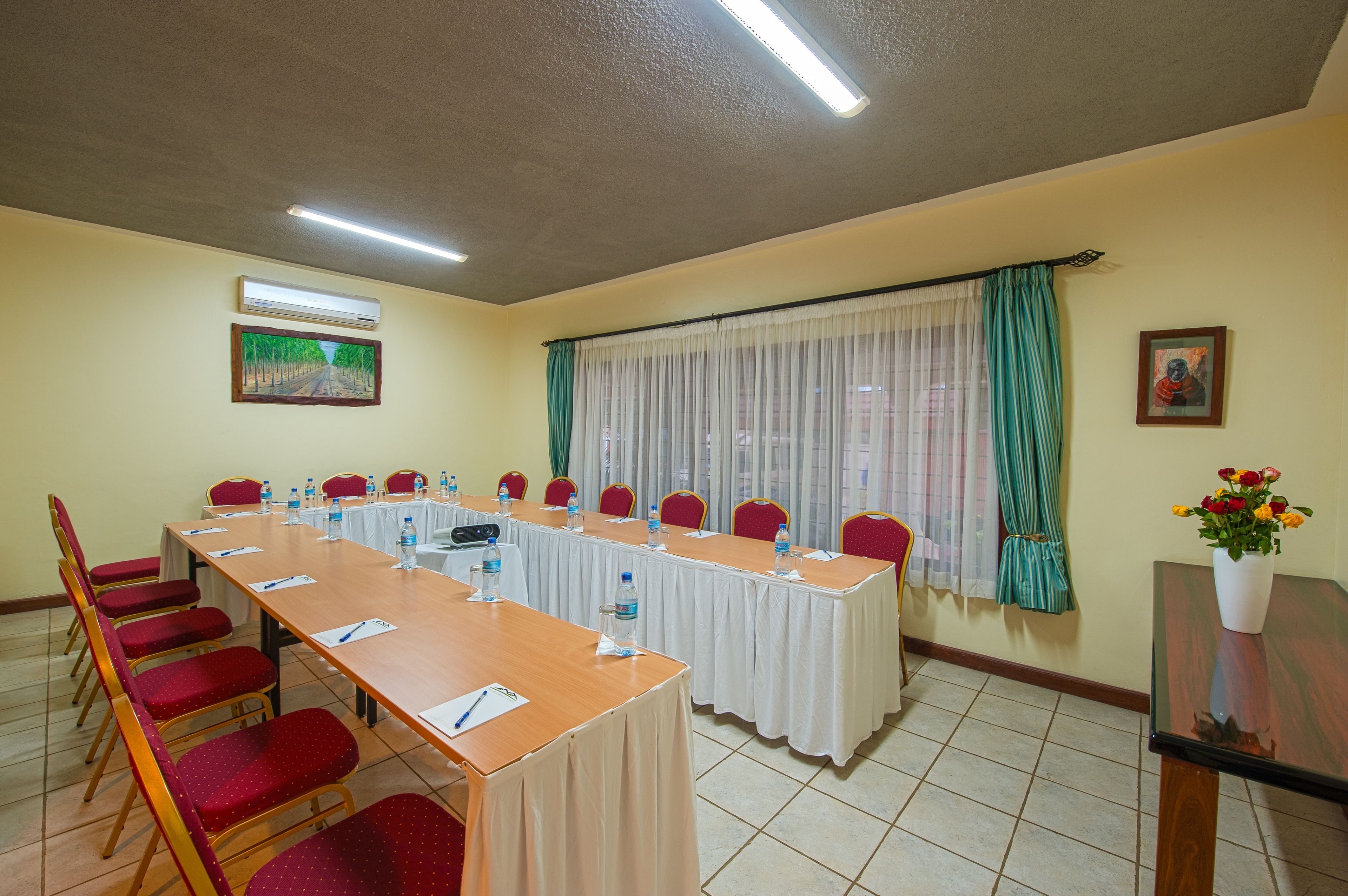 Un salón de conferencias con una larga mesa, sillas y dispensador de agua.