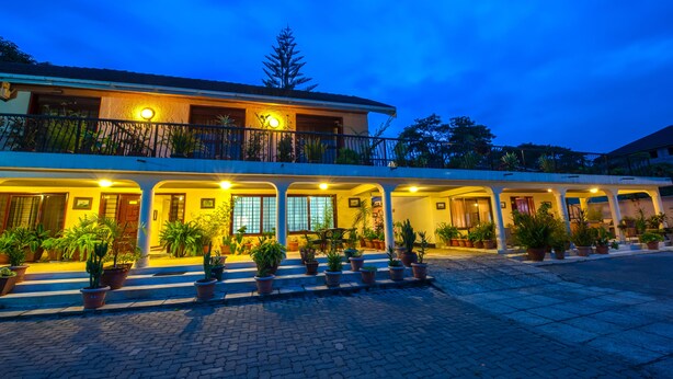A hotel with a covered outdoor area, potted plants, and a well-lit entrance. - The Milimani Lodge (Arusha)