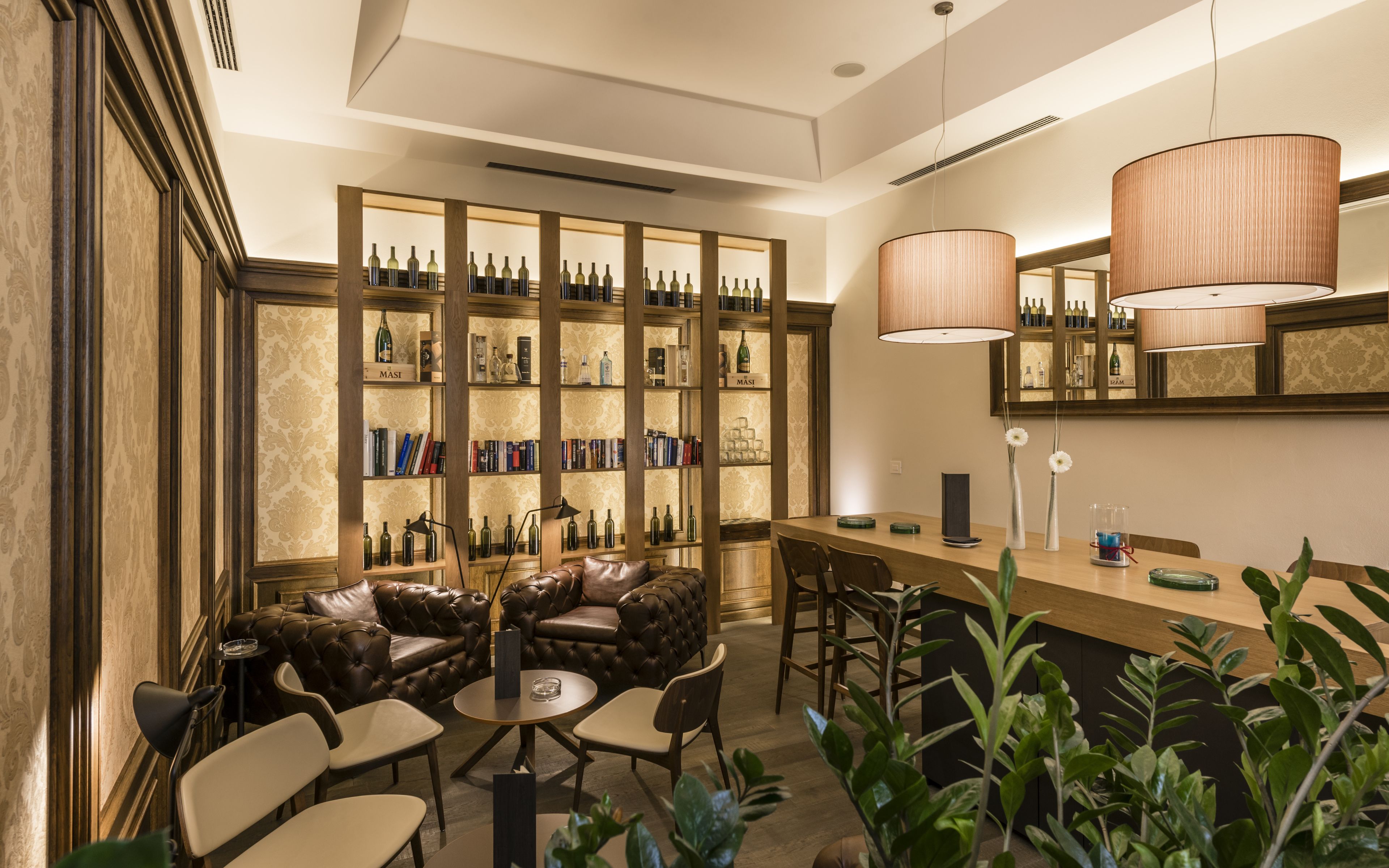 A bar area with leather seating, a bookshelf with bottles, and a counter with a mirror.