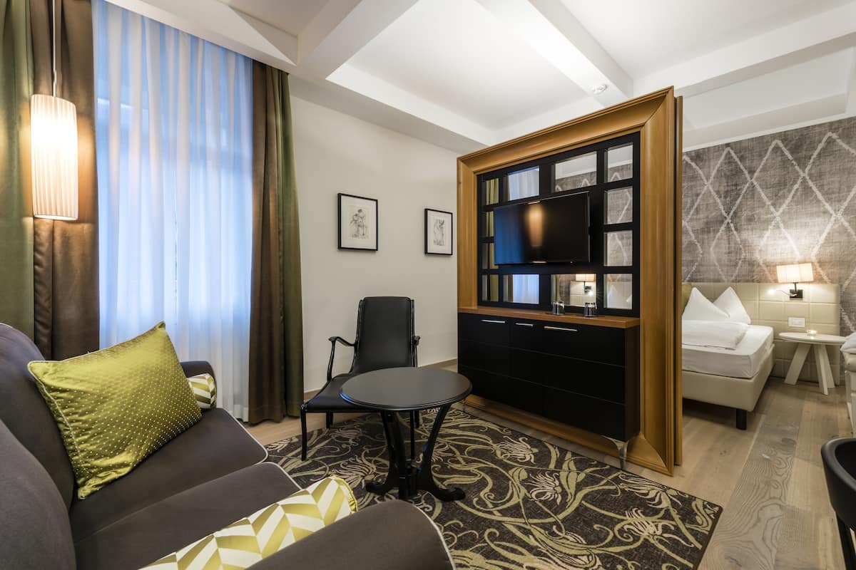 Une chambre d’hôtel moderne équipée d’un canapé, d’une petite table, d’une télévision, d’un lit et d’une table de chevet.