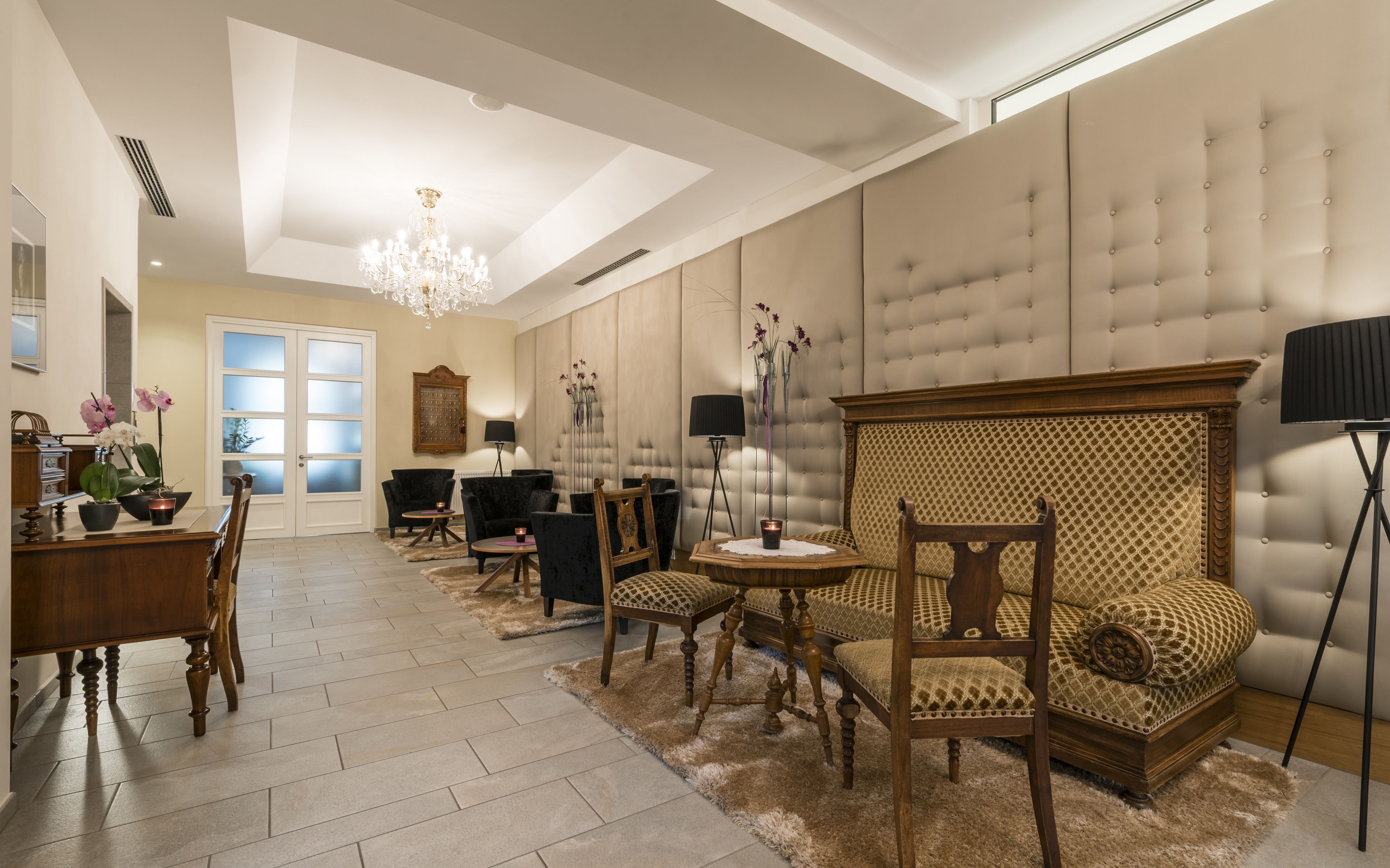 Un salon spacieux avec un plafond haut, un lustre et un grand canapé à capitons.