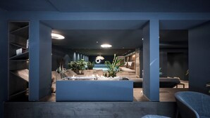 A modern interior with a central seating area, a built-in fireplace, and a staircase leading to an upper level.