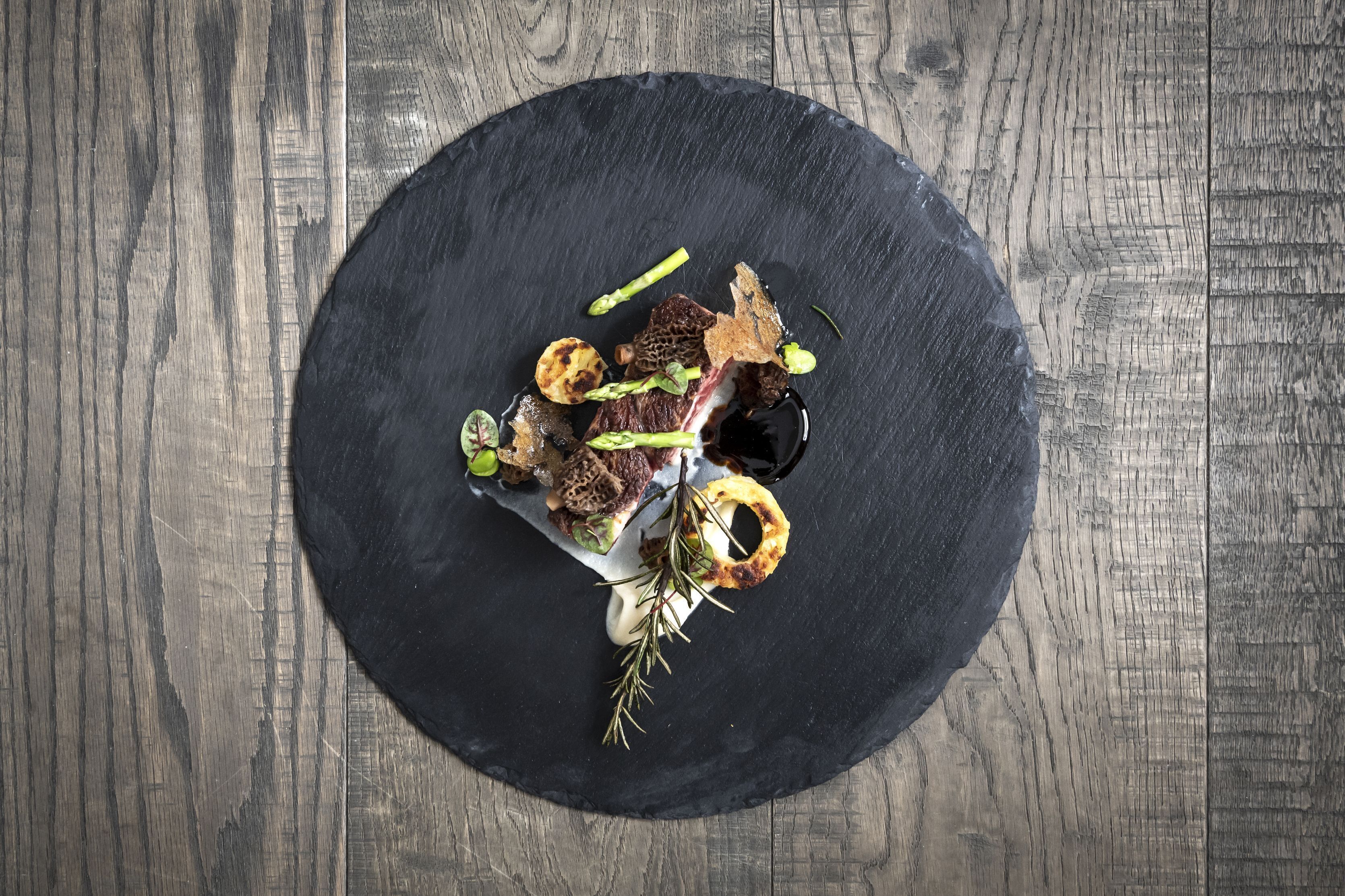 A top-down view of a dining table with a black slate plate, featuring a variety of food items and garnishes.