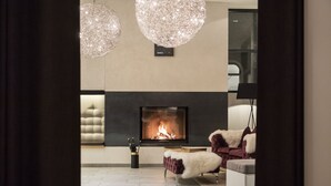 A modern living room with a fireplace, tufted sofa, and two crystal chandeliers.