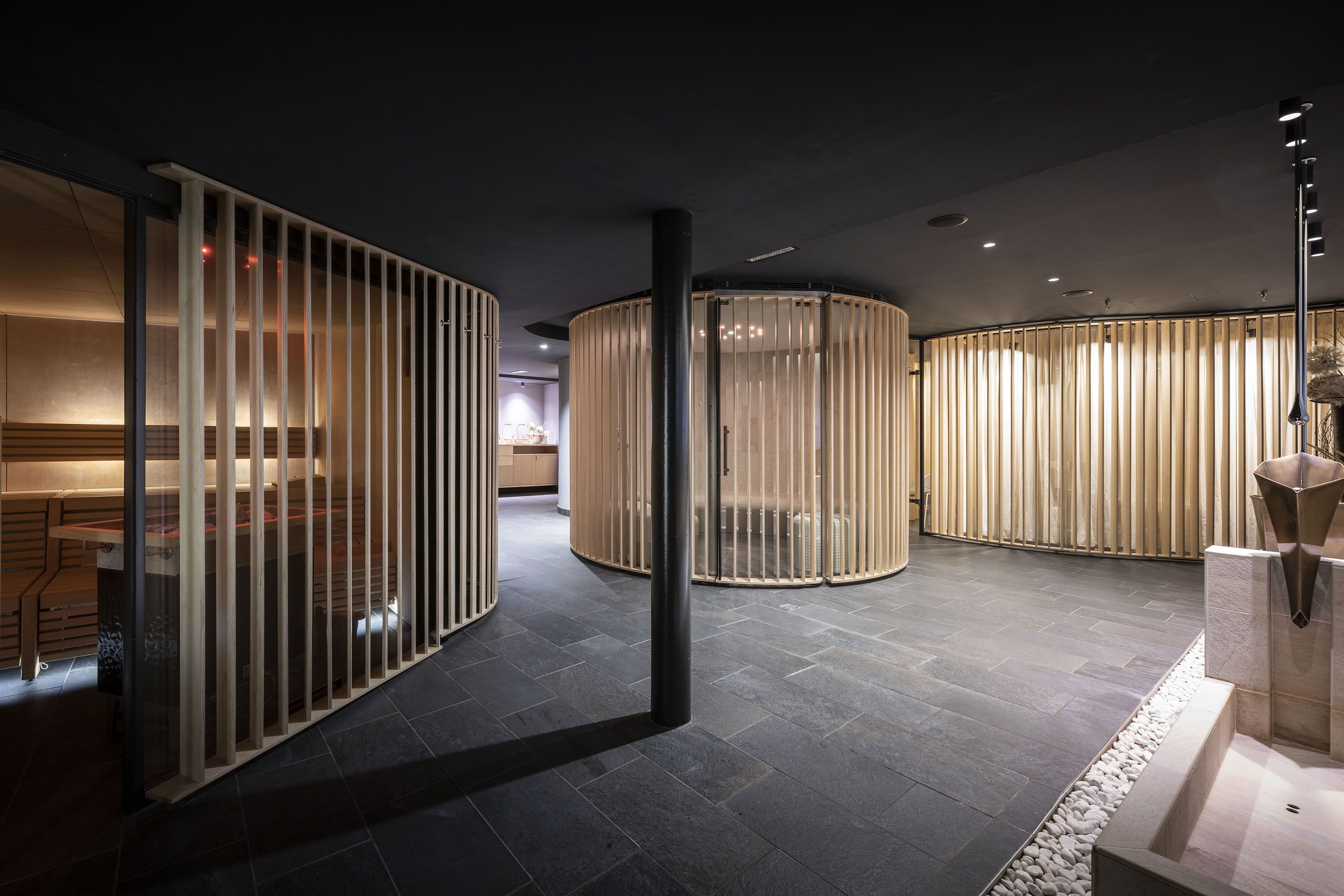 Un interior moderno con separaciones curvas, piso de piedra y diseño minimalista.