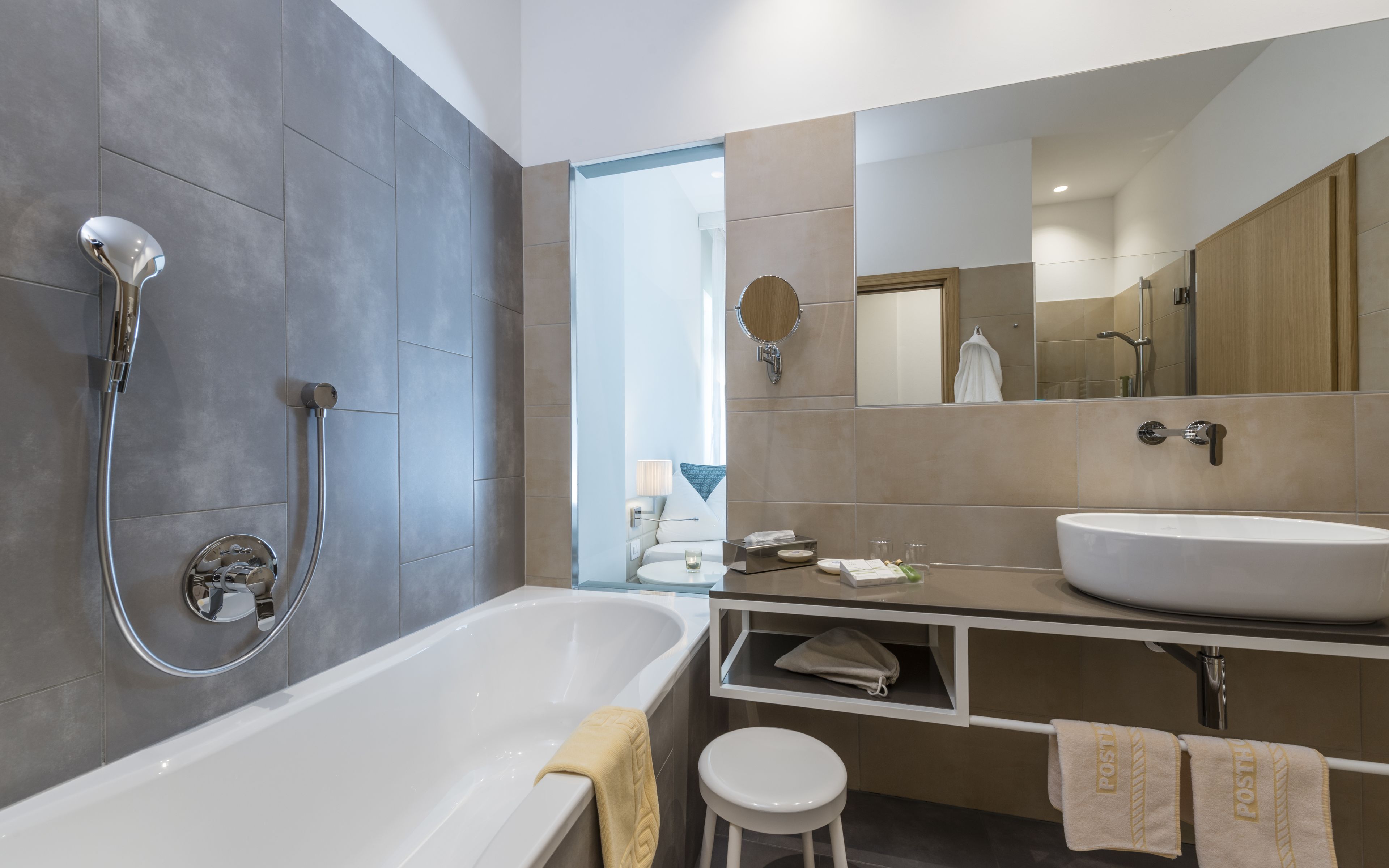 Un bany modern amb banyera, un mirall gran, un lavabo i una dutxera.