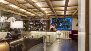 A modern bar area with wooden beams, leather seating, and a view of the outdoors.