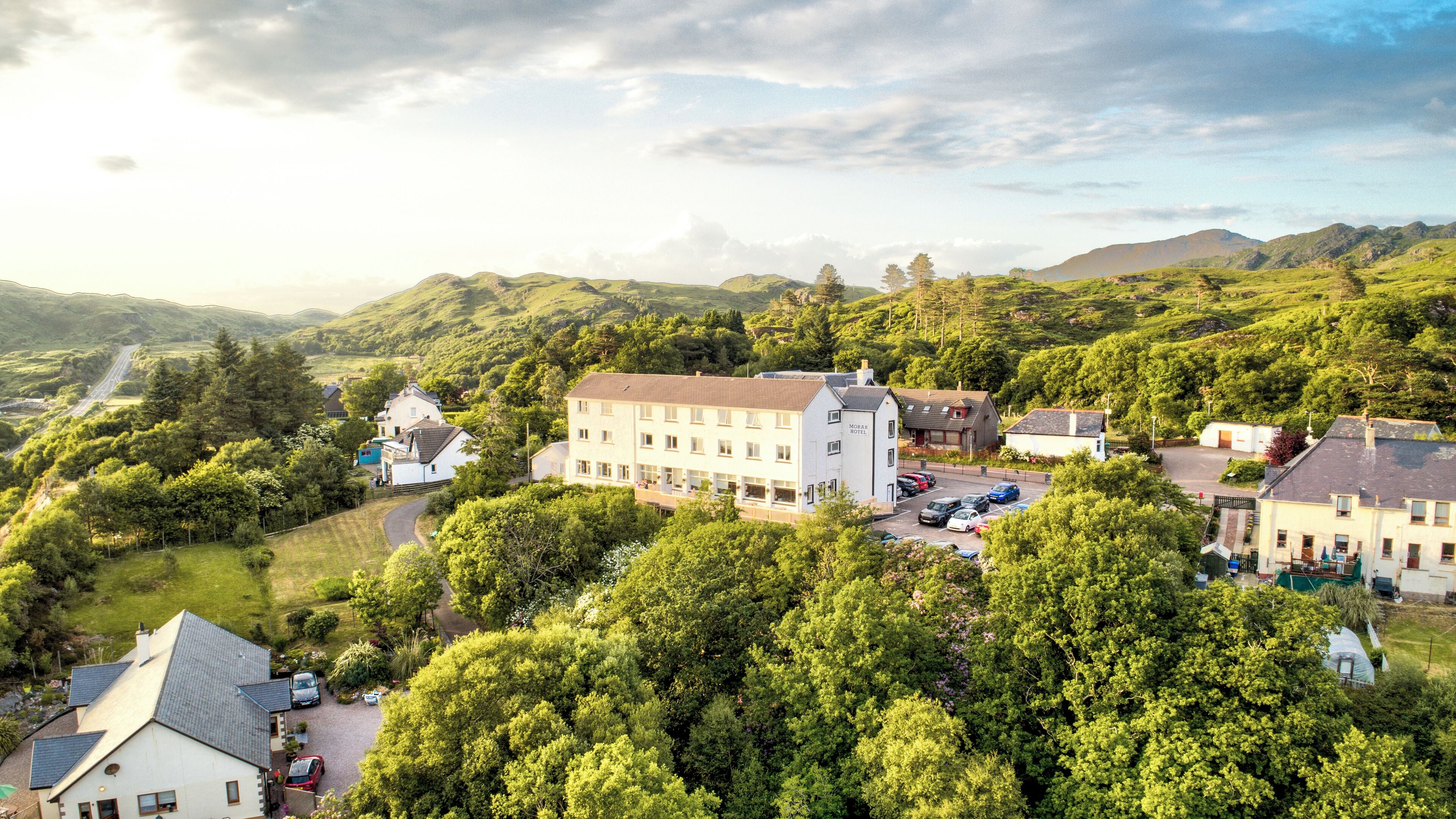 A hotel with multiple buildings, surrounded by lush greenery and hills.