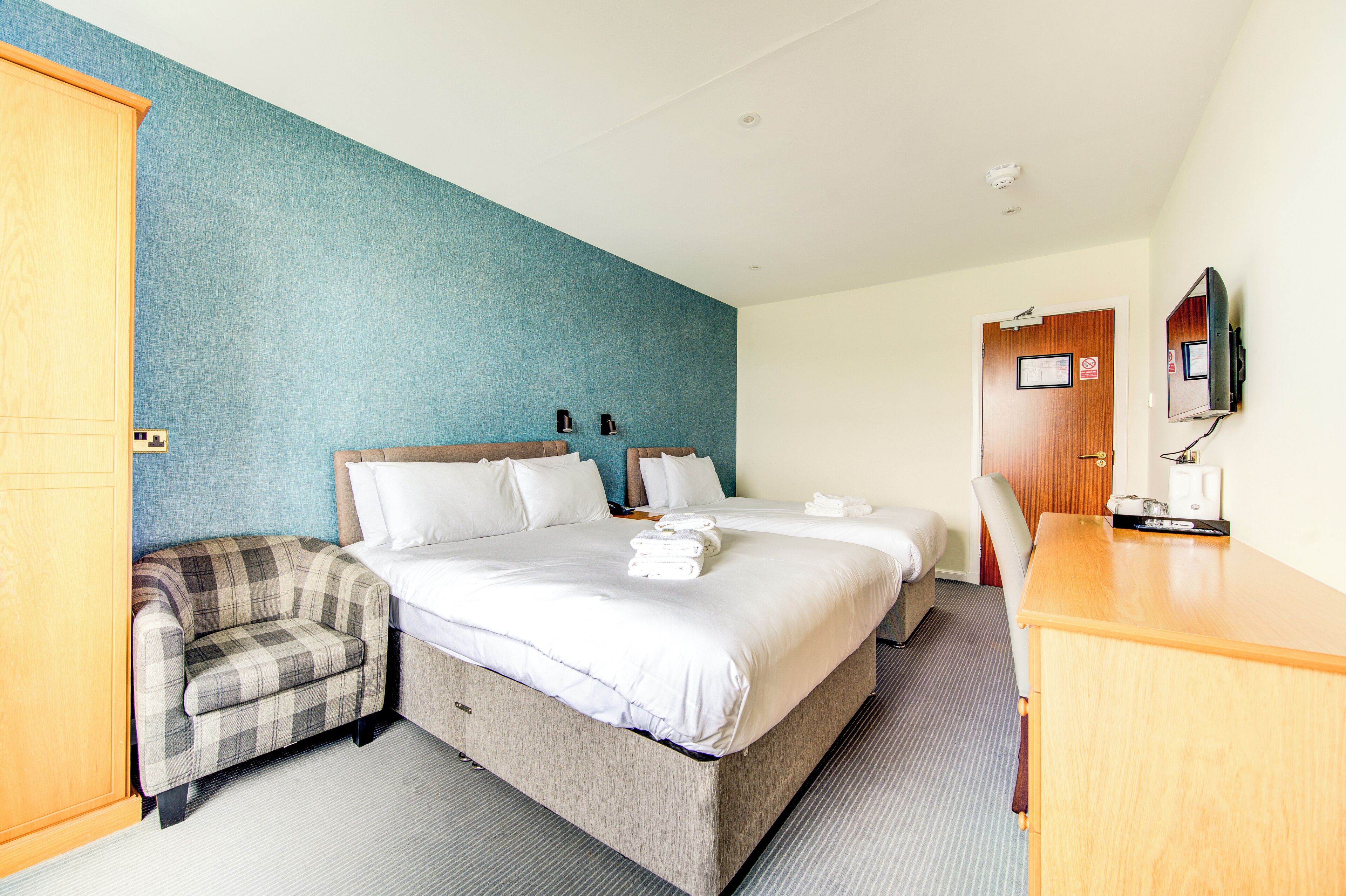 A hotel room with a large bed, a chair, a desk, and a television.