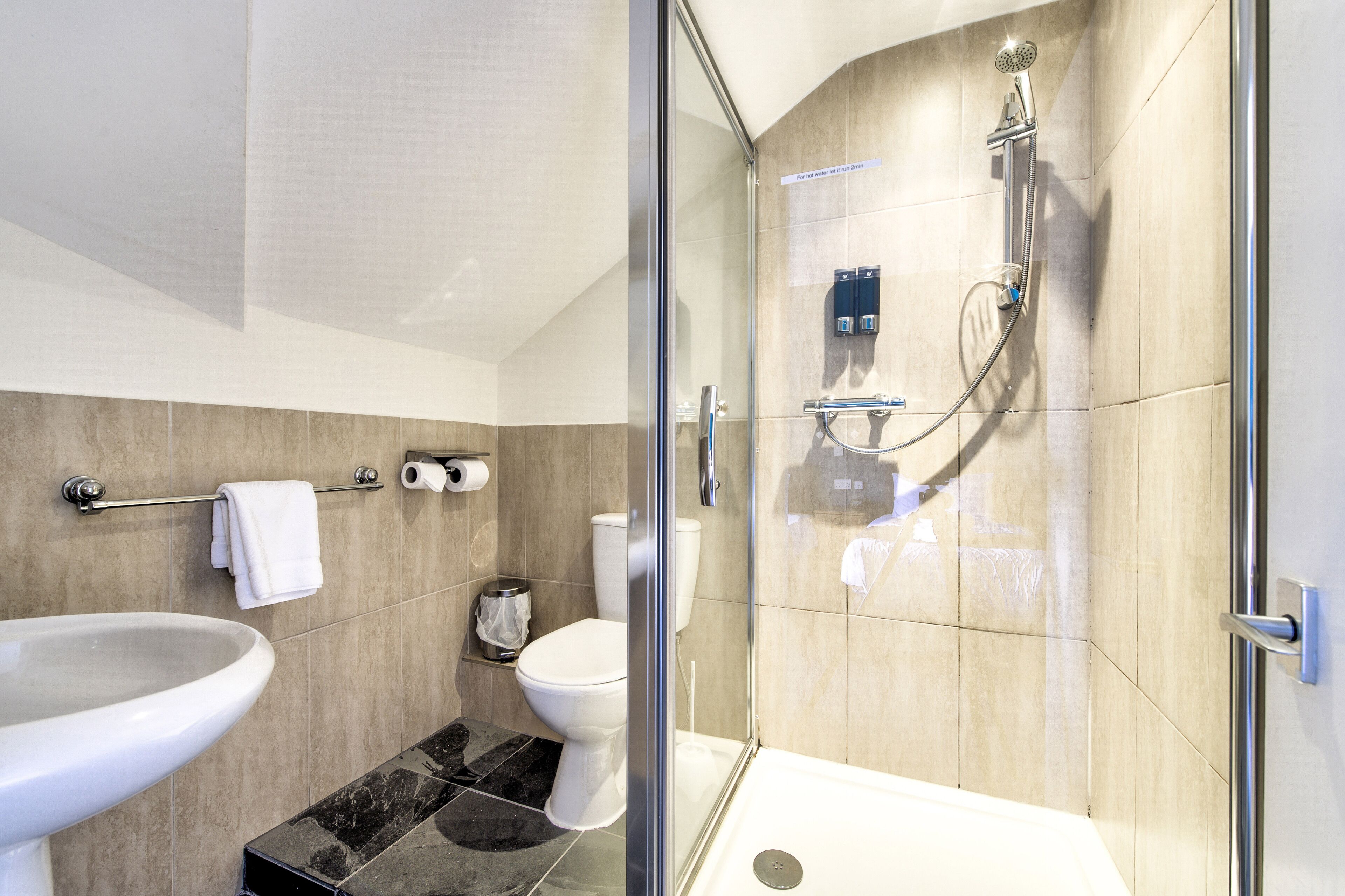 A modern bathroom with a glass-enclosed shower, a white sink, and a toilet.