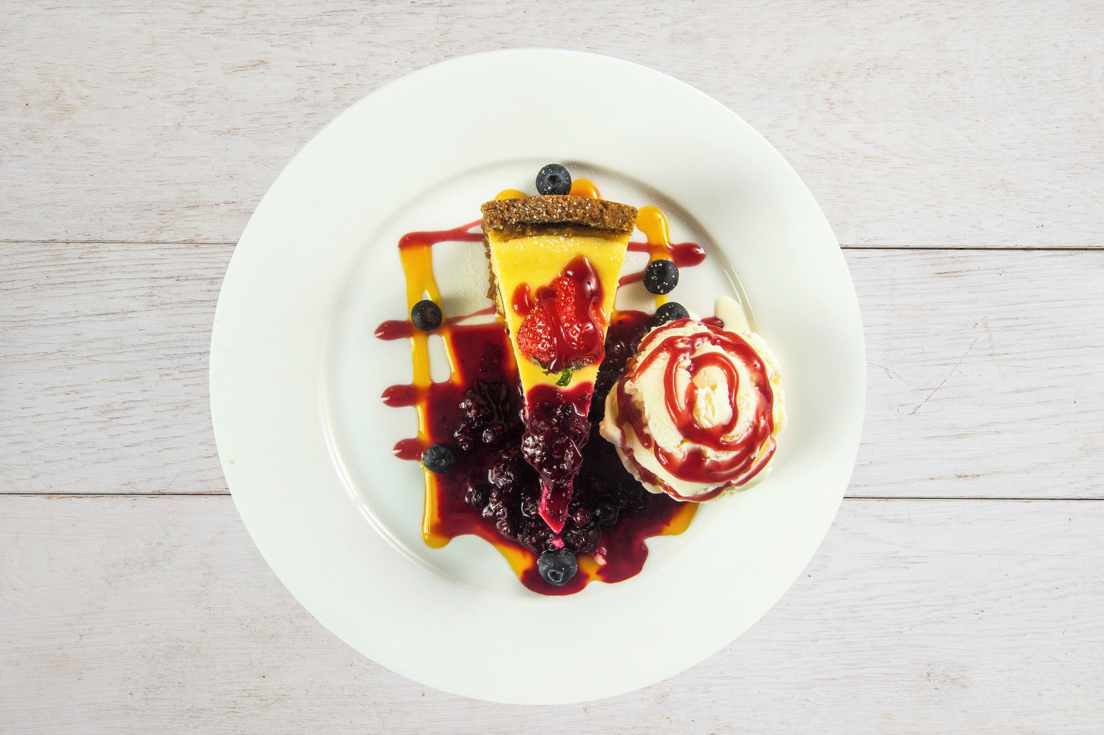 A dessert plate with a slice of pie, blueberries, and a scoop of ice cream on a white plate.