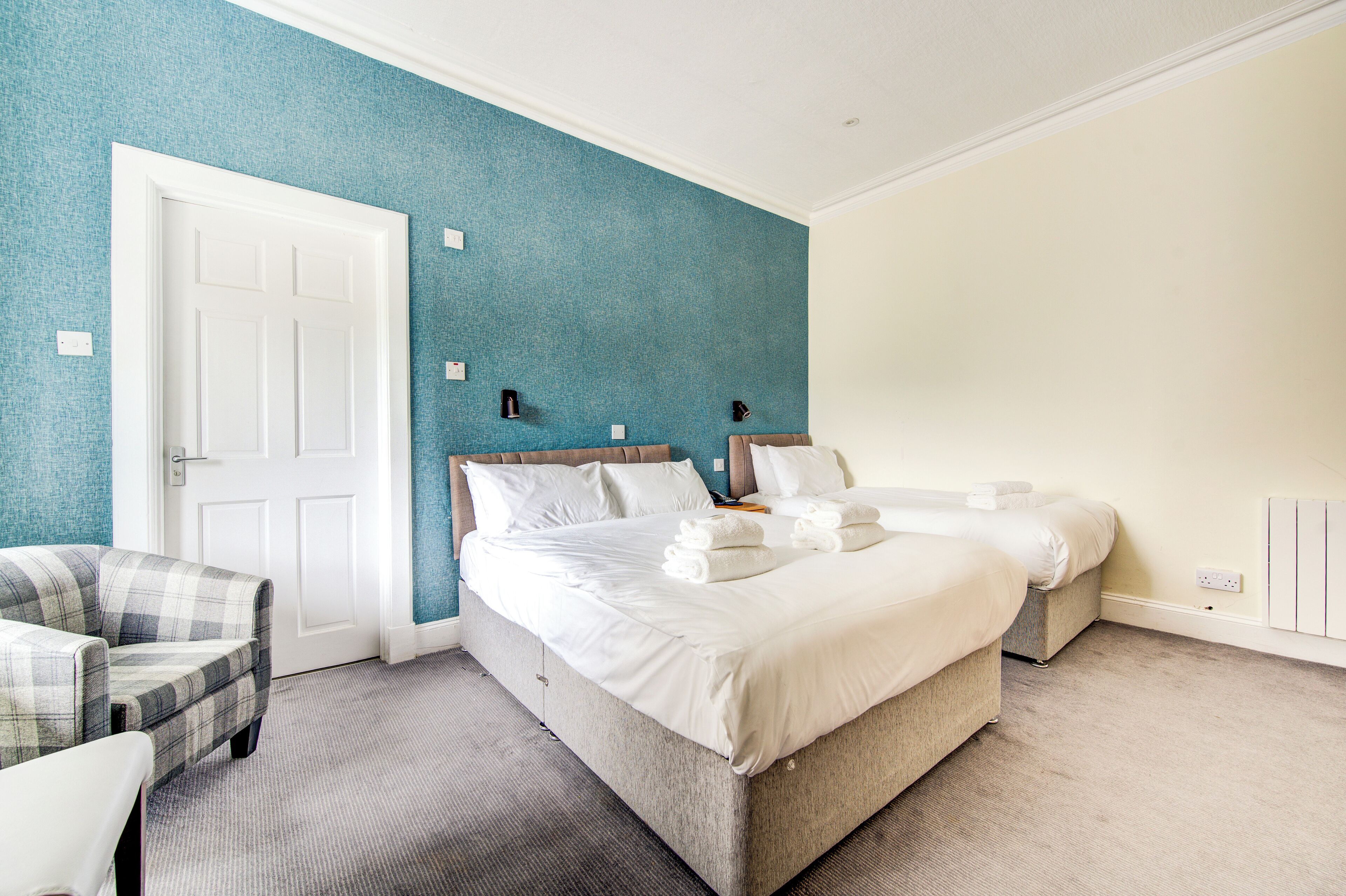 A hotel room with a large bed, a chair, and a small table.