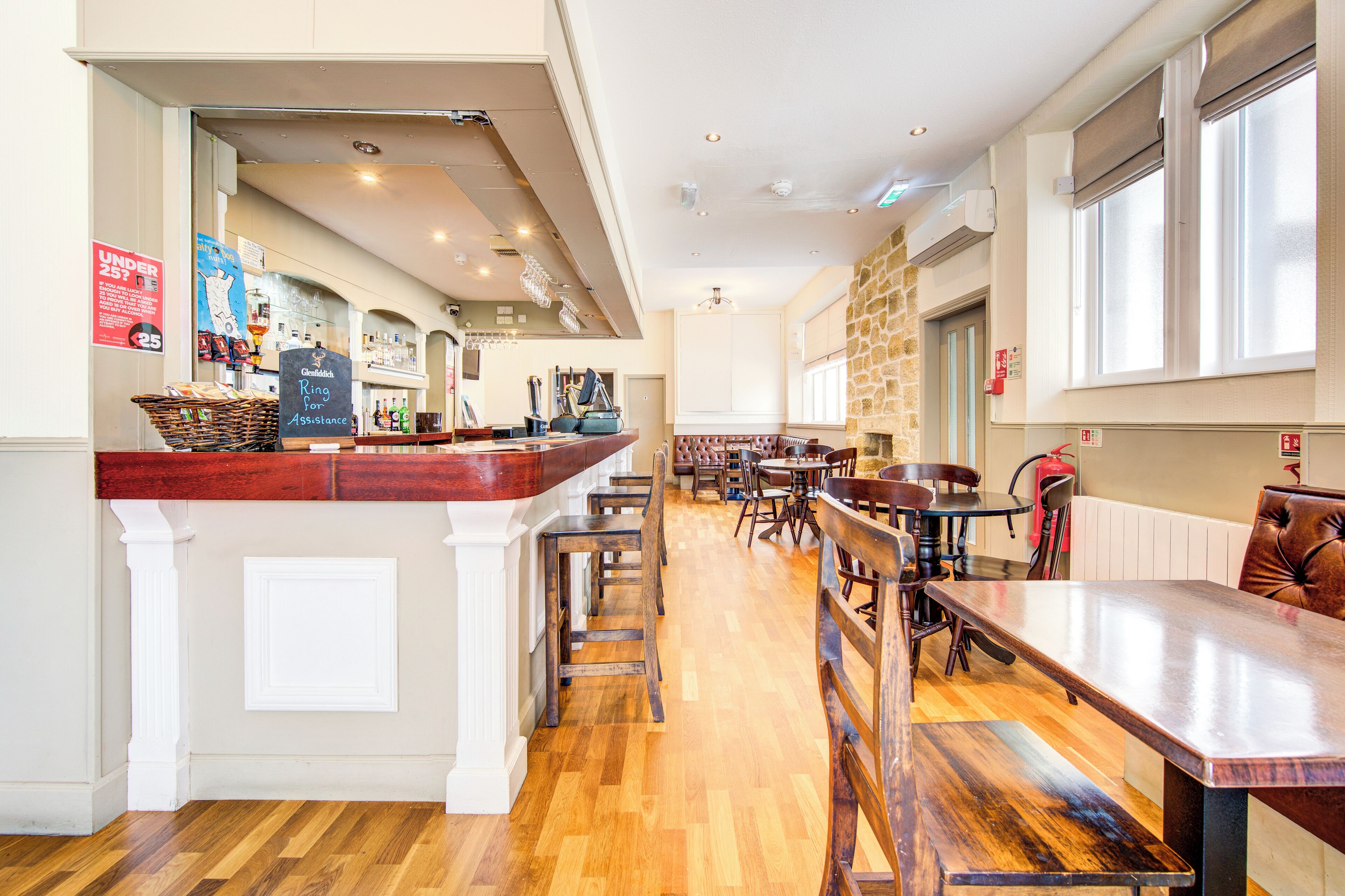 Un restaurant doté d’un bar, de planchers en bois et offrant différents types de sièges, notamment des banquettes et des tables.
