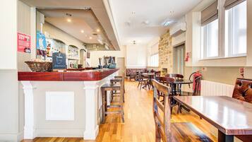 Un restaurant doté d’un bar, de planchers en bois et offrant différents types de sièges, notamment des banquettes et des tables.