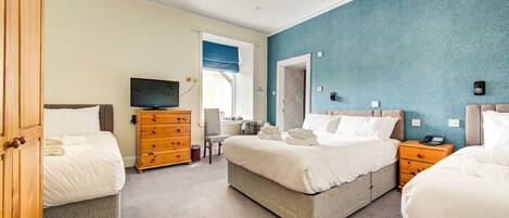 A hotel room with two beds, a TV, a wooden dresser, and a chair.