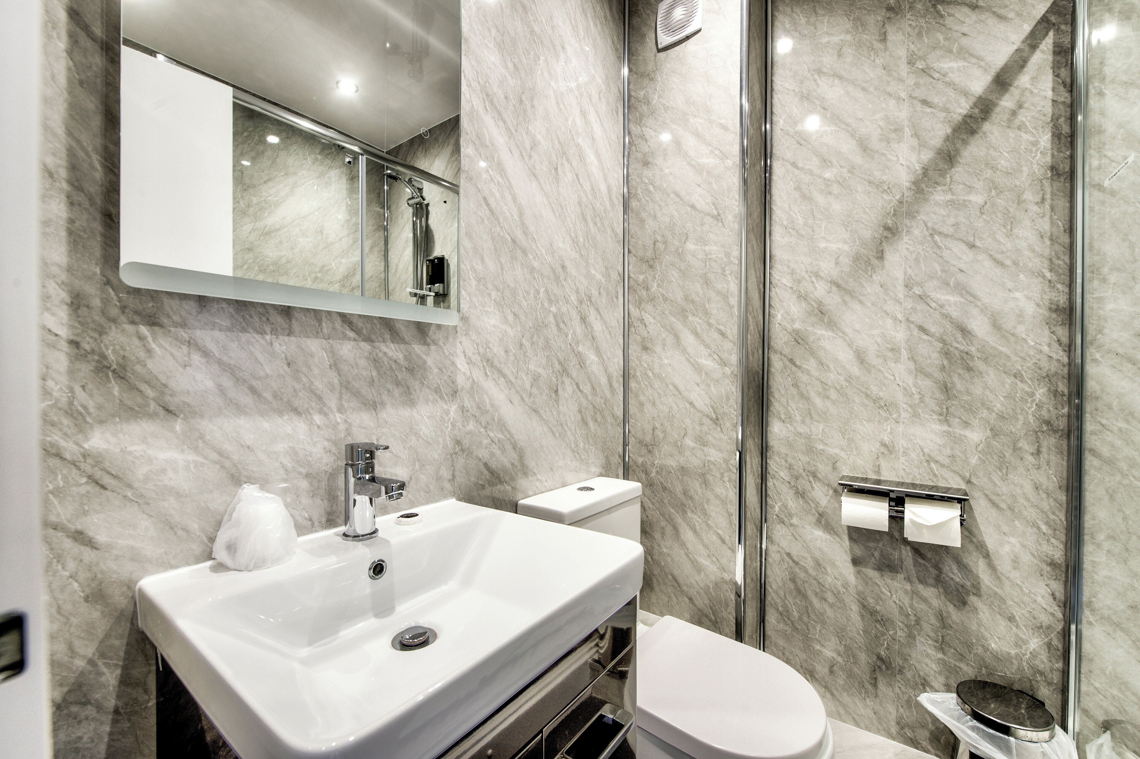 A modern bathroom with a marble sink, toilet, and shower.