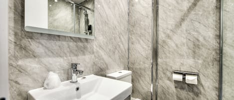 A modern bathroom with a marble sink, toilet, and shower.