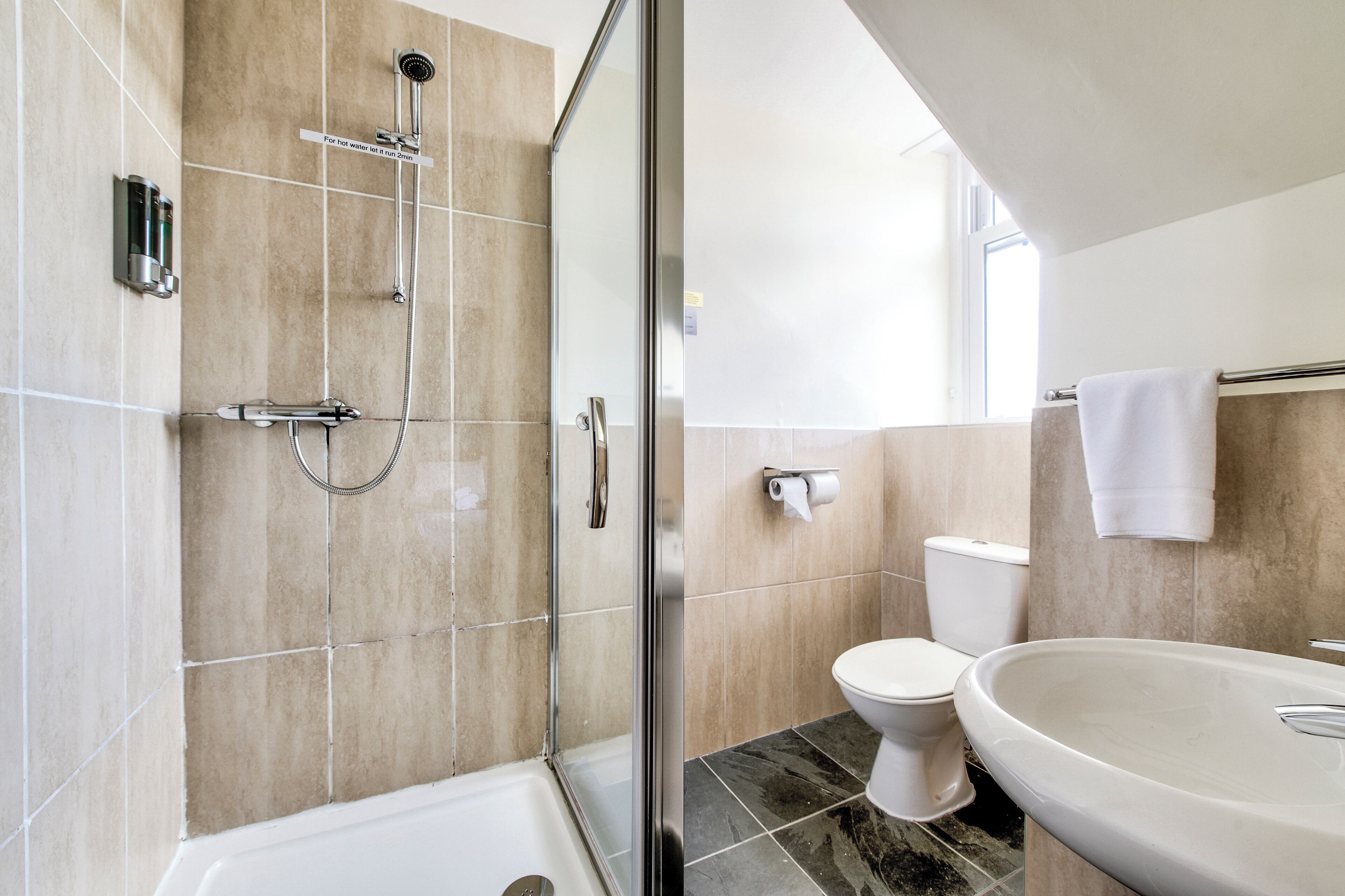 Une salle de bain moderne avec une douche à parois de verre, des toilettes blanches et un grand lavabo.