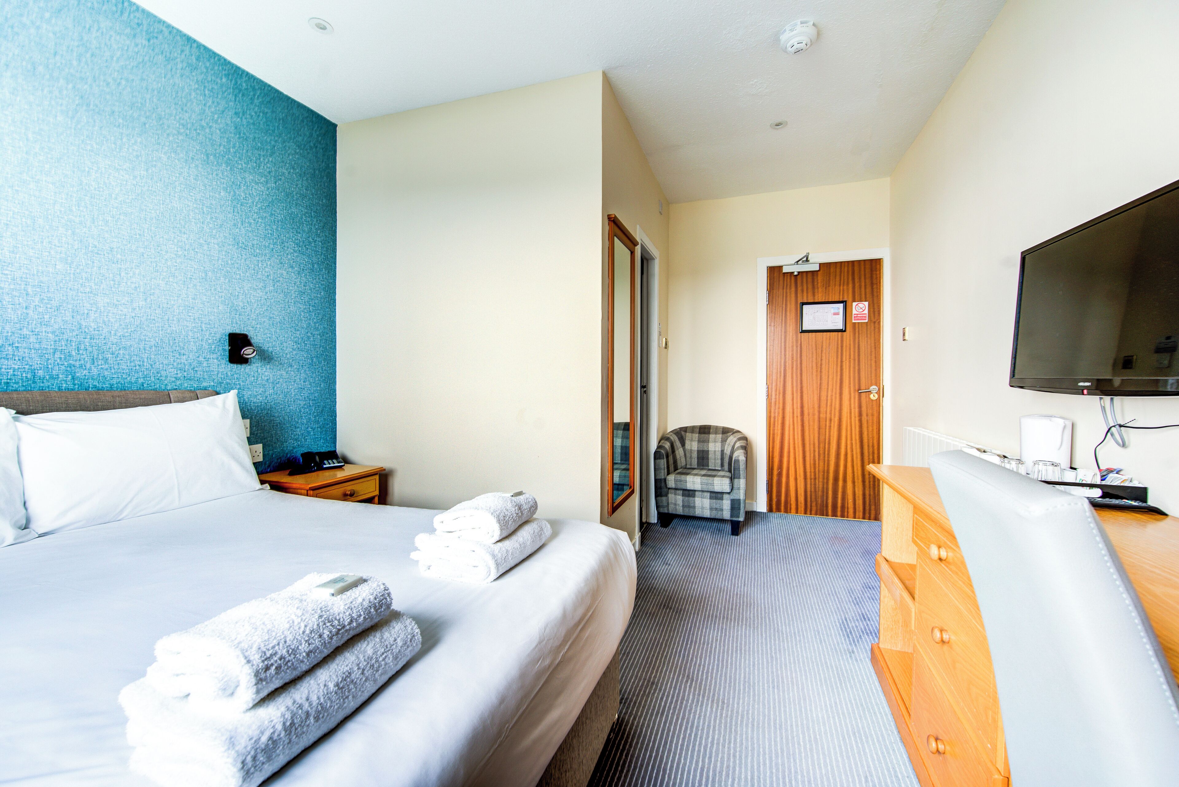 A hotel room with a bed, a chair, a desk, and a television.
