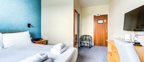 A hotel room with a bed, a chair, a desk, and a television.