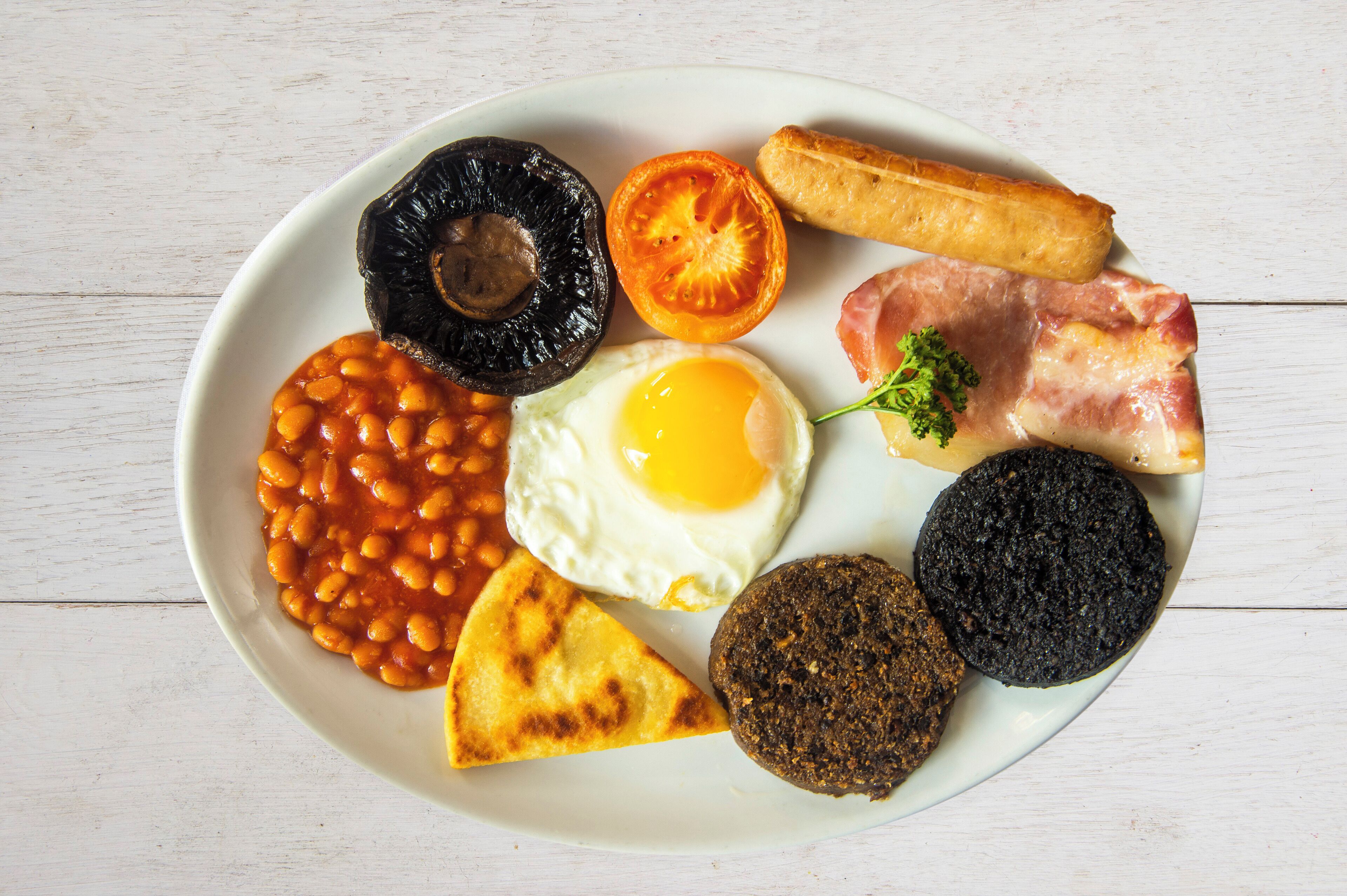Un plat amb aliments per esmorzar, com ara ous, fesols, salsitxes i torrades.