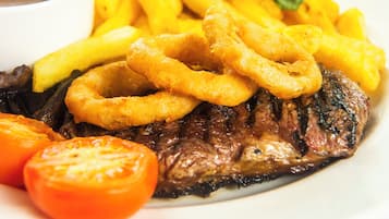 Un plato con bistec, aros de cebolla y papas fritas.