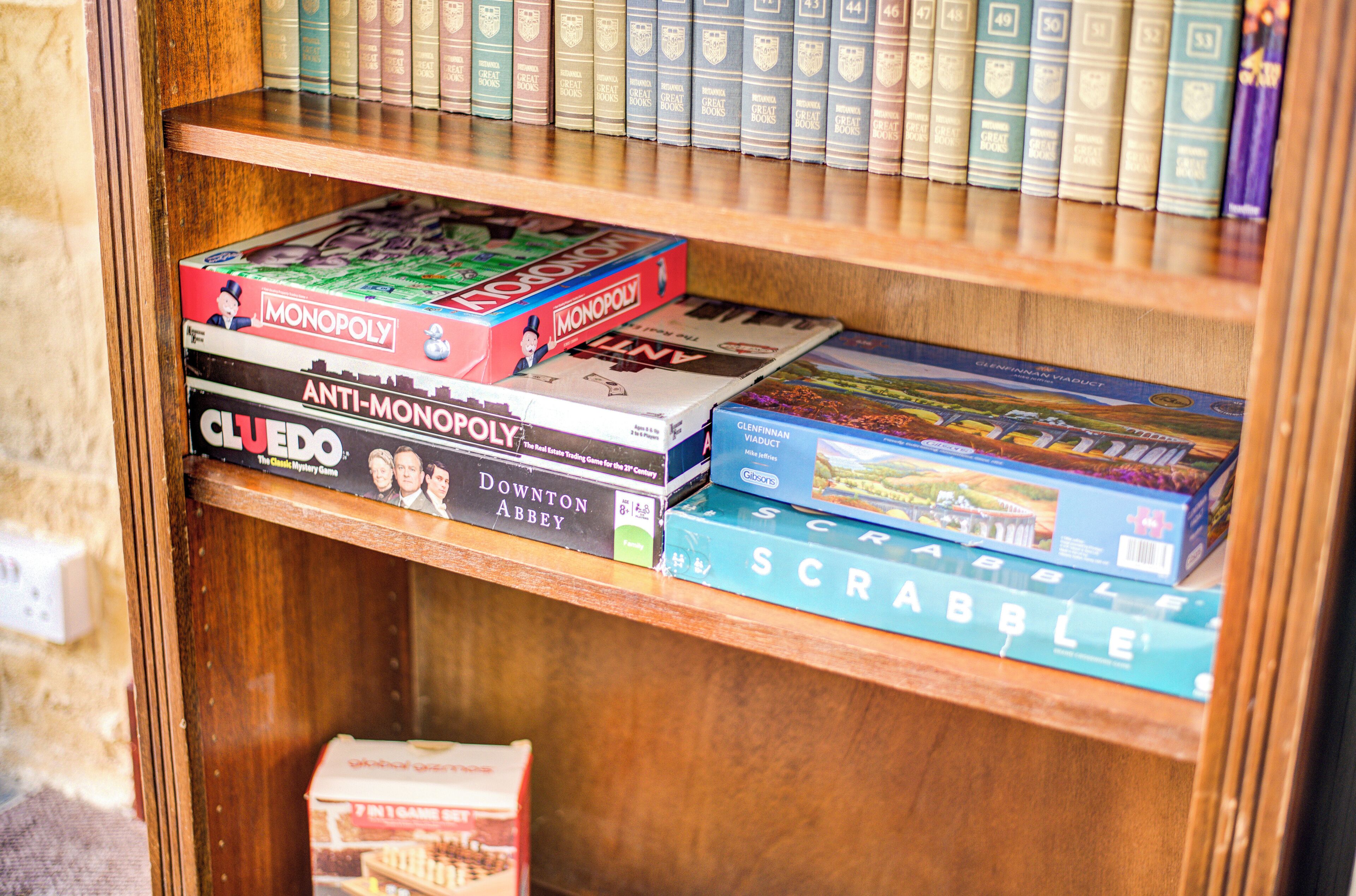 A wooden bookshelf with various board games and books.