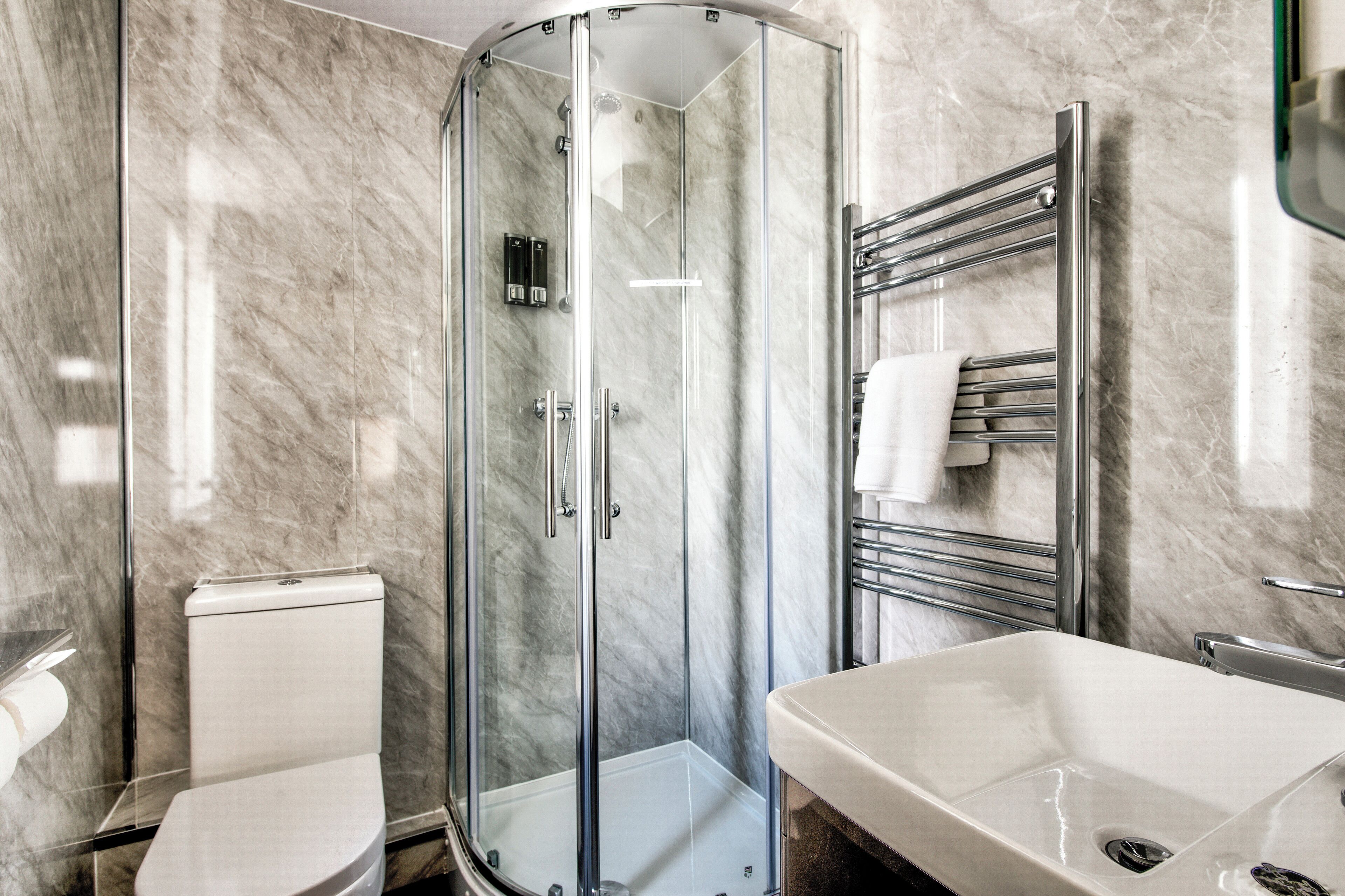 A modern bathroom with a glass-enclosed shower, a white toilet, and a large sink with a mirror.