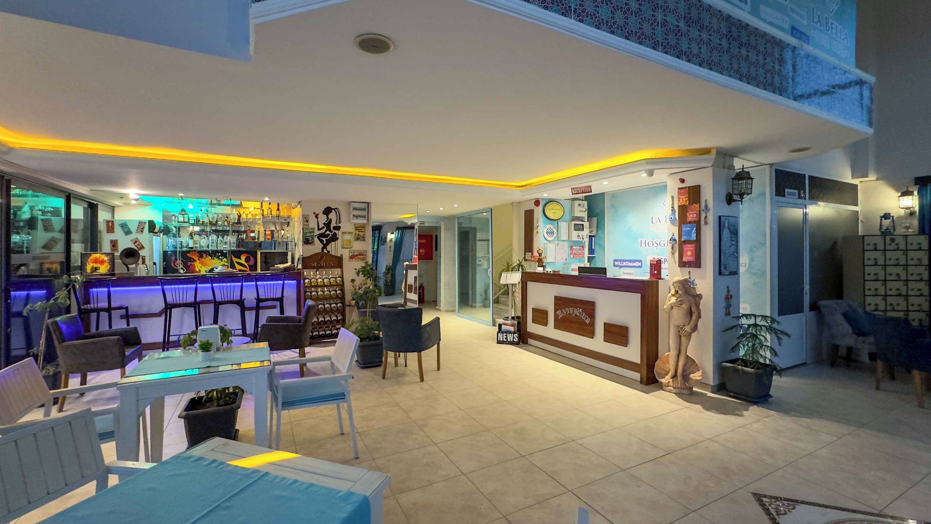 A hotel lobby with a reception desk, bar area, seating, and a staircase.