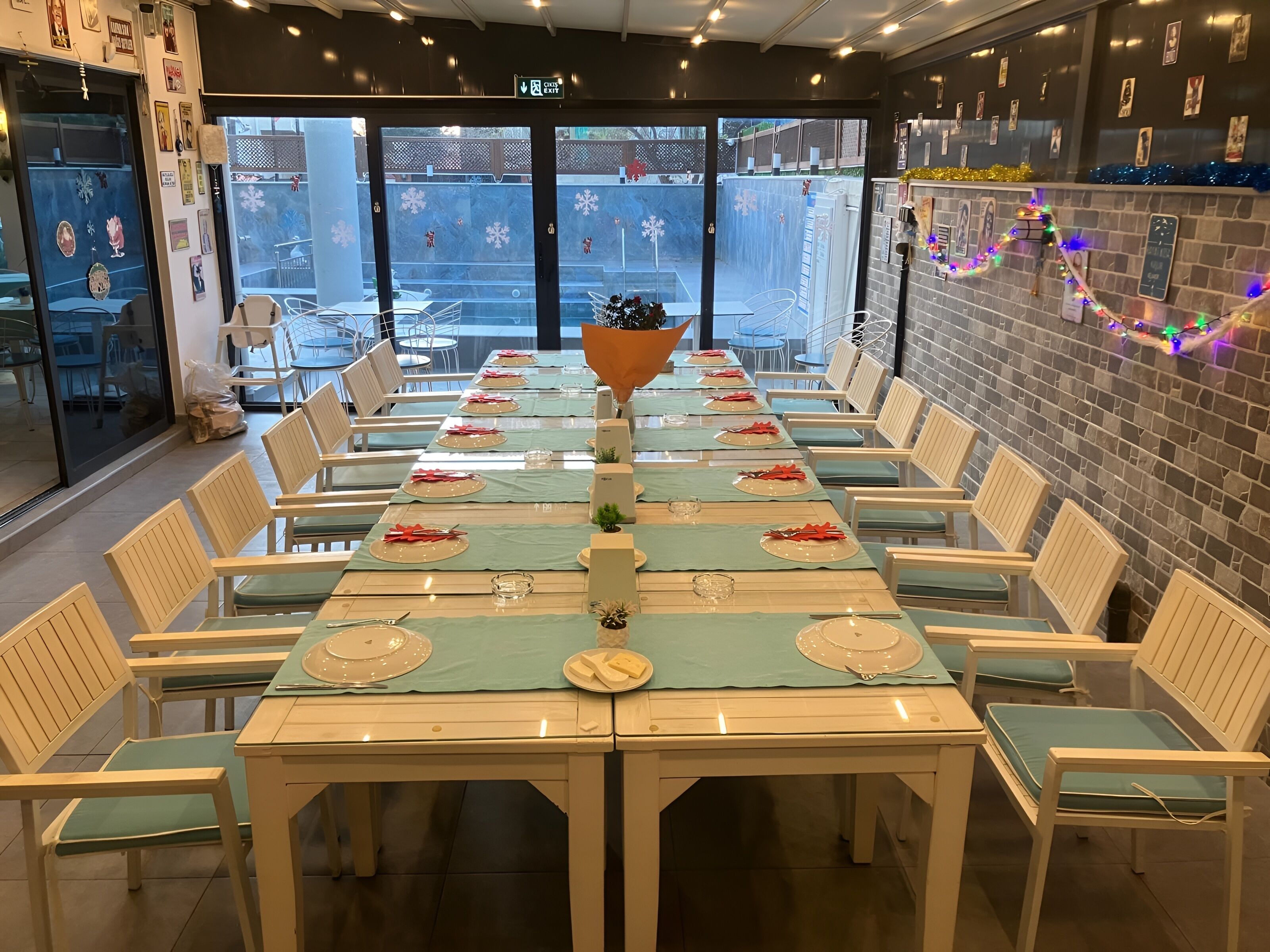 A dining area with long tables set for multiple guests, chairs, and a decorative centerpiece.